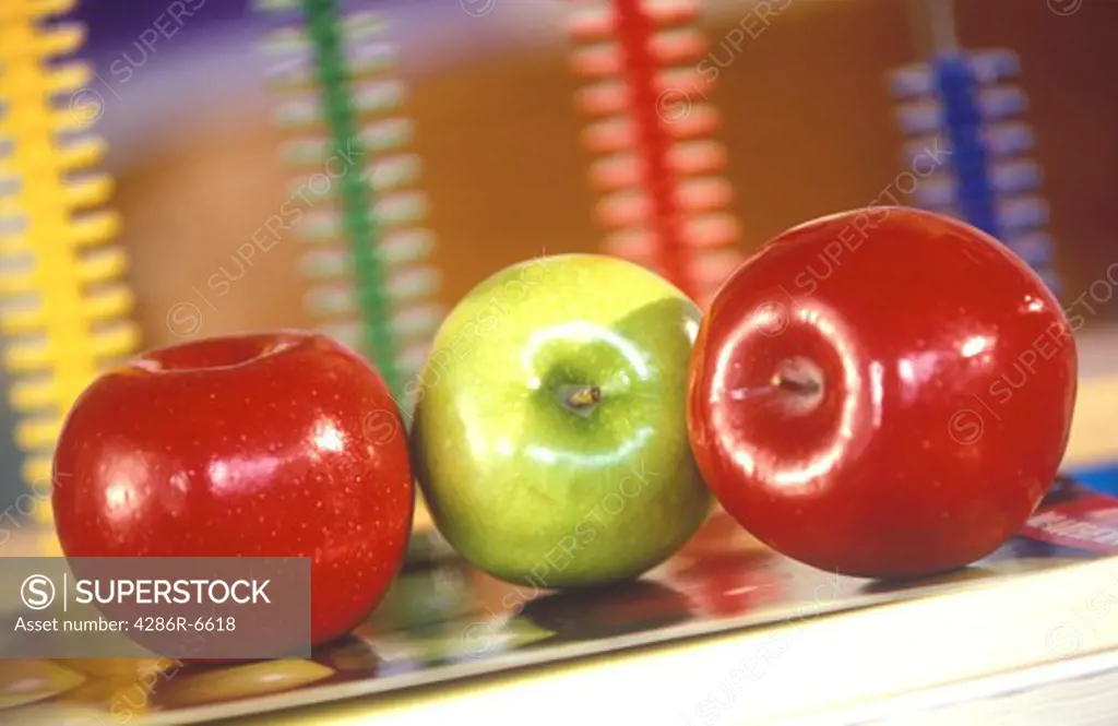 Three shinny apples on a teachers desk.