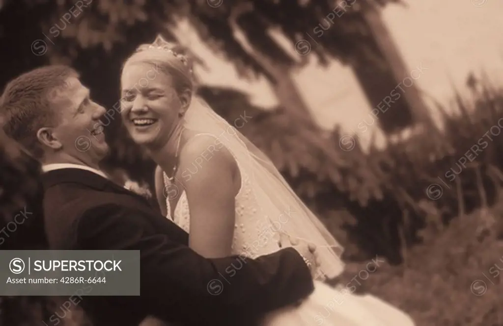Black and white image of a young bride and groom hugging.