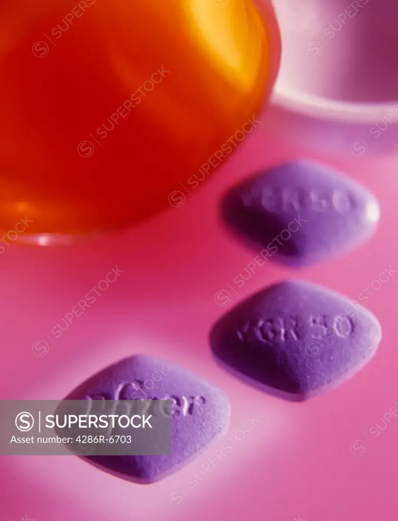 Three blue pills lying by a open pill container.
