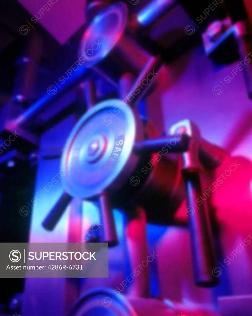 Vertical close up of a bank vault door lit with colored lights.