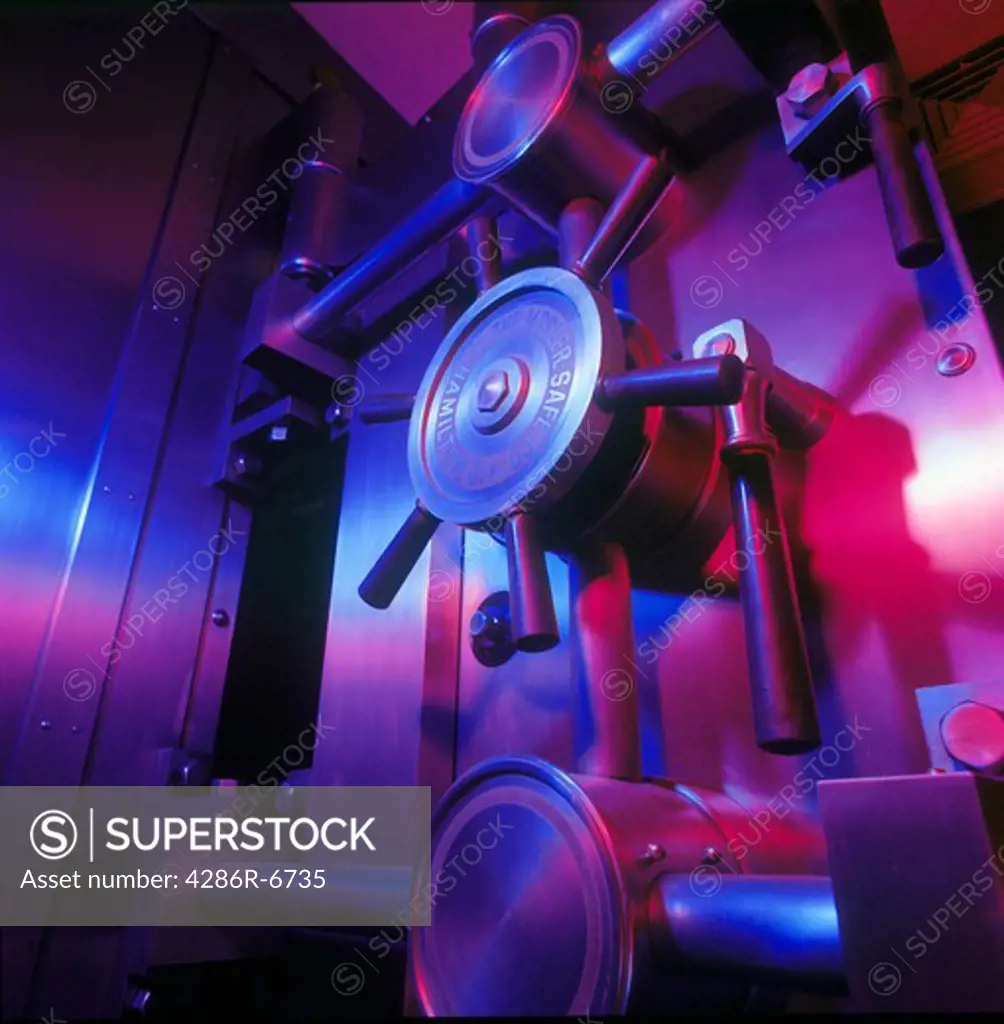 Square close up of a bank vault door lit with colored lights.