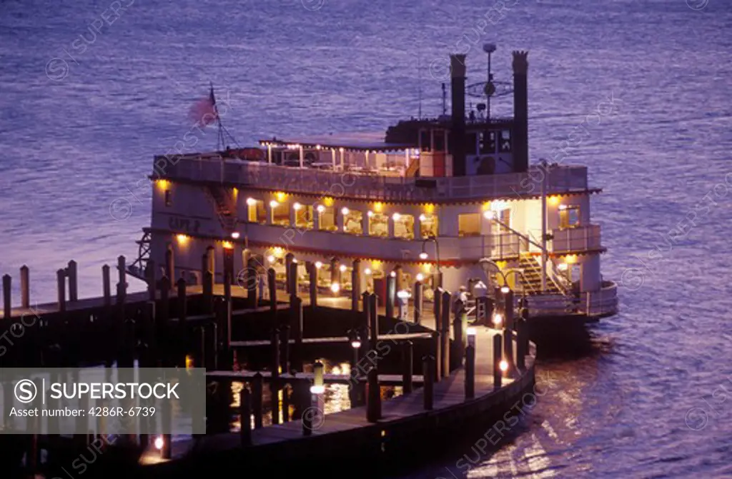 An old fashion paddle wheel boat preparing for departure at sunset.
