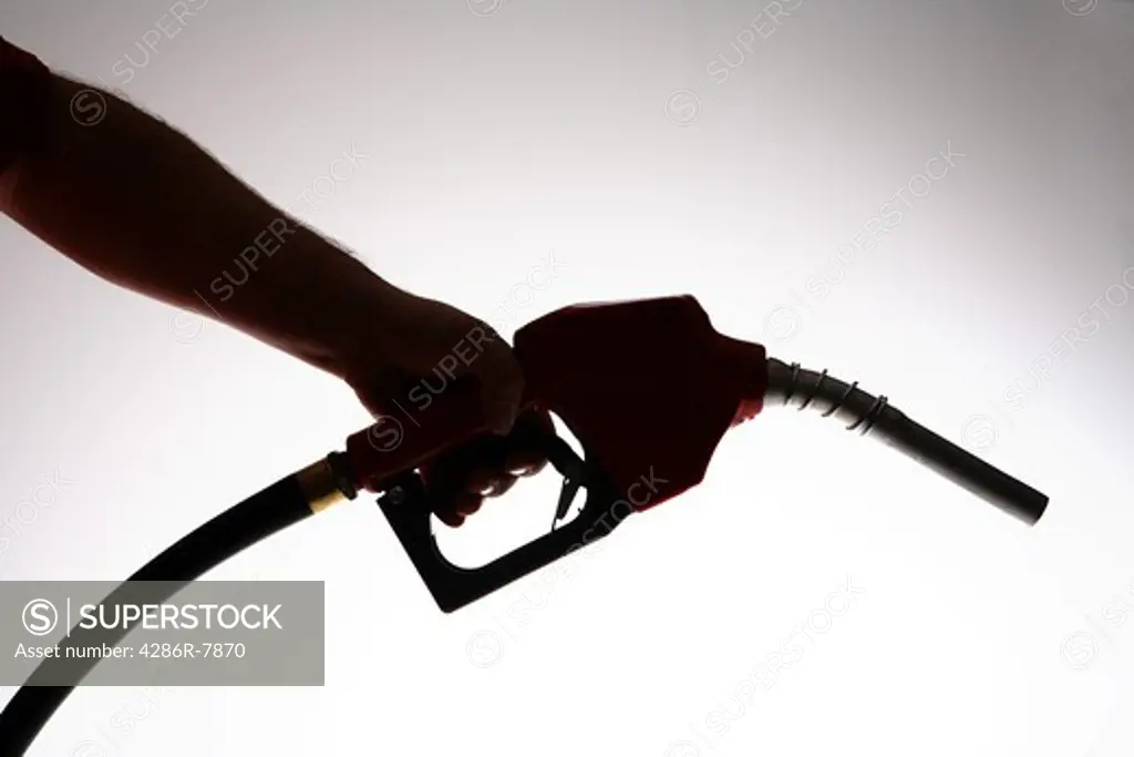 Silhouette of hand holding gas nozzle