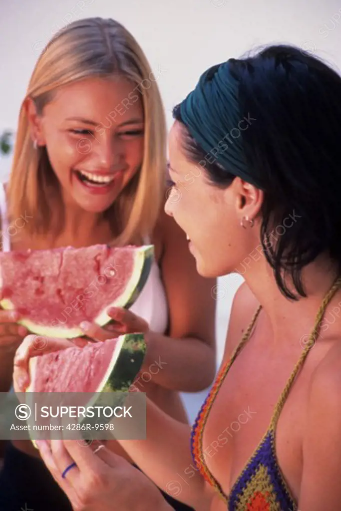 Pleasurable summer day as two young attractive women enjoy eating watermelon.
