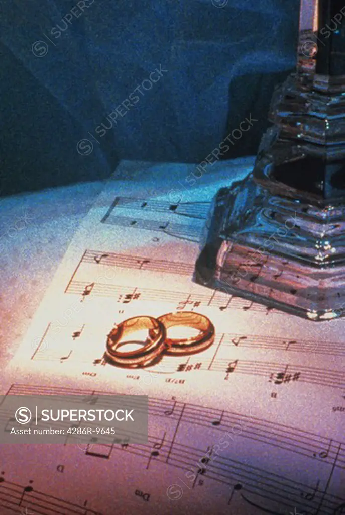 Conceptual image of wedding rings set atop of a music sheet denoting marriage and love.