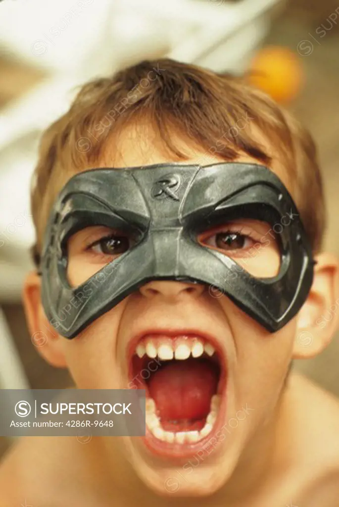 Portarit of a young boy wearing a mask and shouting at the camera.