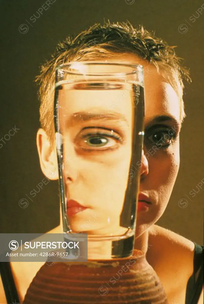 Close-up of a womans face being refracted by a glass of water.