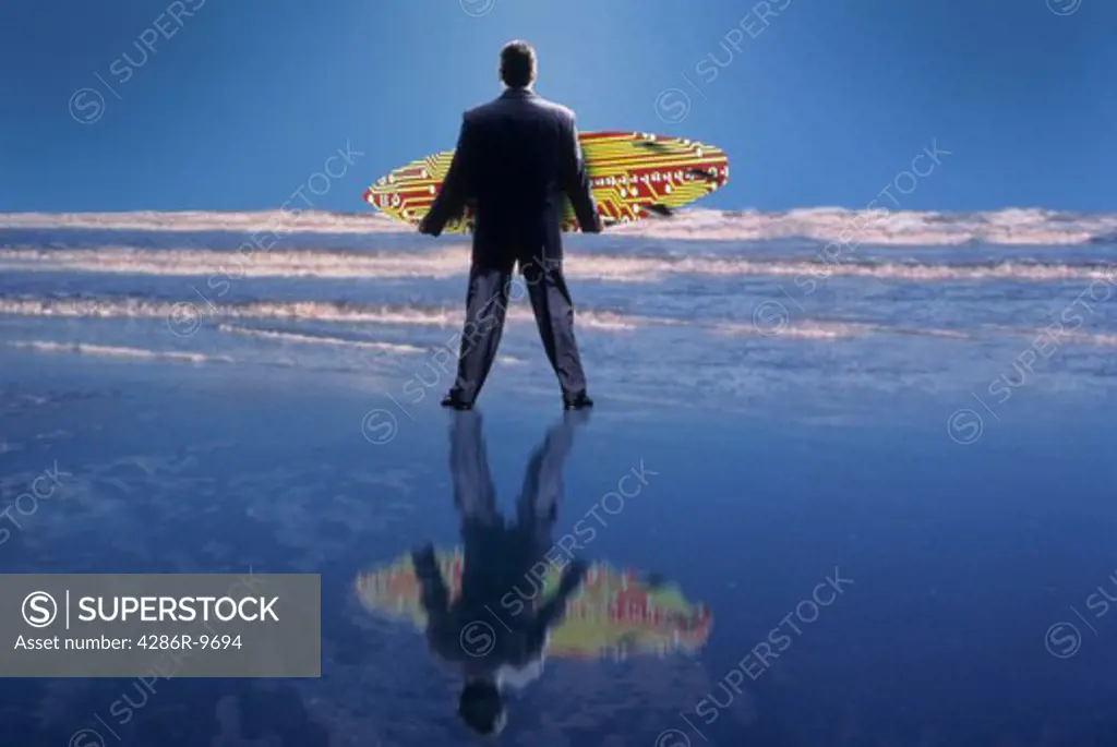Businessman holding a surfboard standing in the shore.