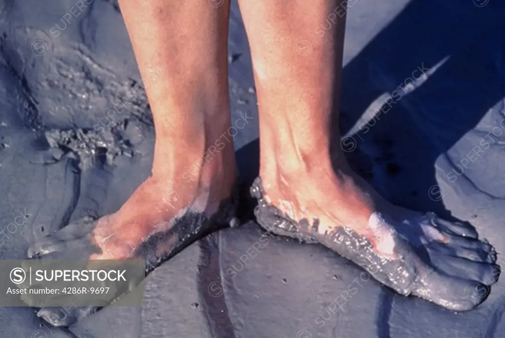 Pair of feet standing in wet clay.