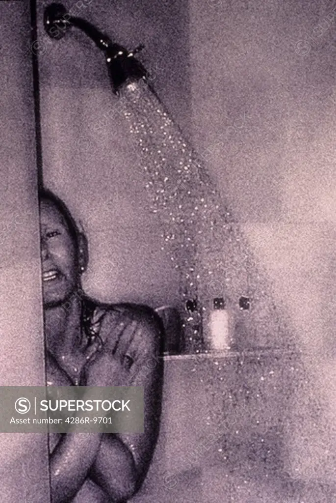 Woman taking a shower with her arms crossed in some kind of discomfort.