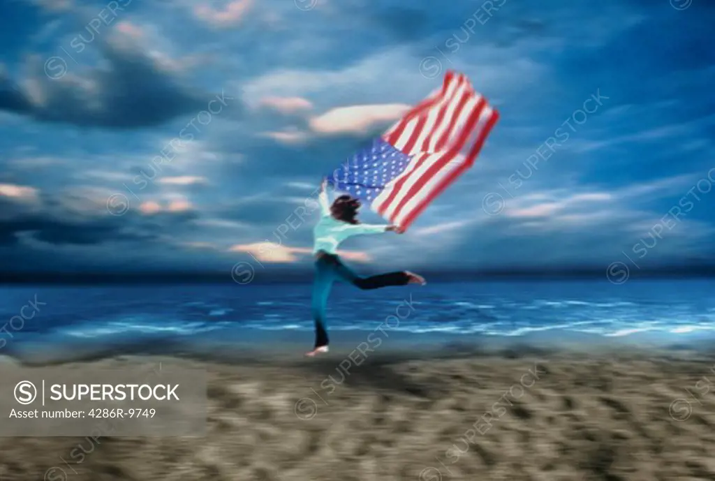 Woman running along the beach flying a flag of the U.S. in the wind.