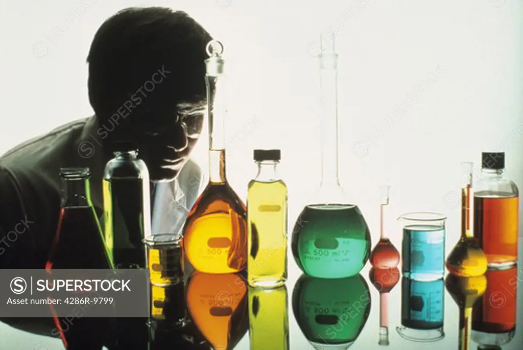 Male scientist over seeing a multitude of chemically filled beakers and flasks.