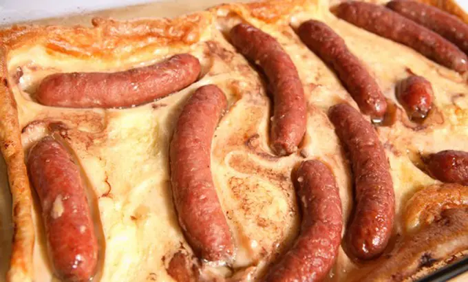 A serving dish full of 'toad in the hole' a traditional cheap English dish of sausages in Yorkshire pudding batter.