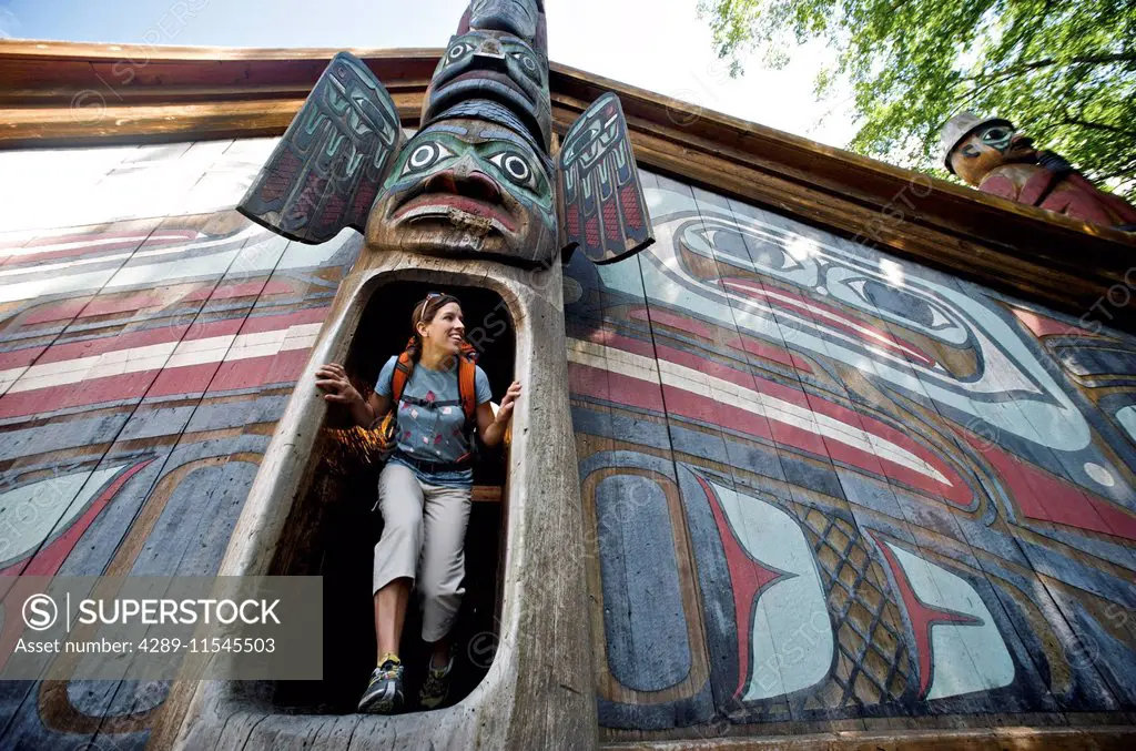 Woman Explores The Clan House At Totem Bight State Historical Park Near Ketchikan, Southeast Alaska, Summer