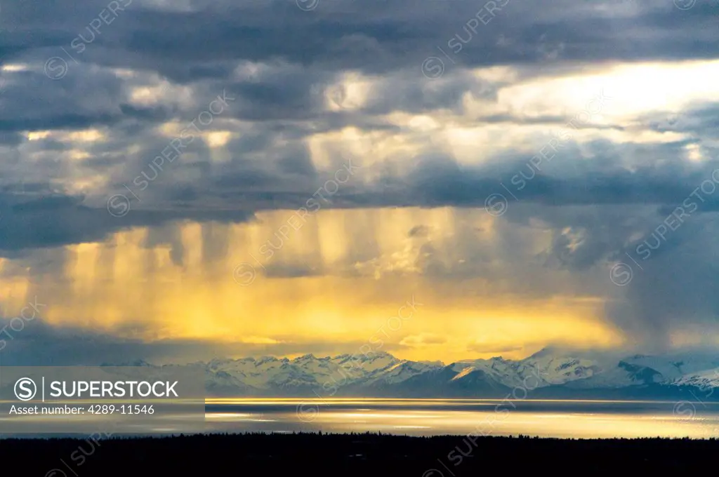 Sunrays peek through clouds over Cook Inlet with the Chigmit Mountains in the background, Kenai Peninsula, Southcentral Alaska, Spring