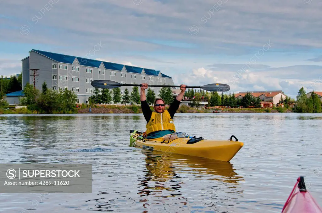 Man raises his arms in triumph after paddling the Chena River in Fairbanks,Interior Alaska, Summer