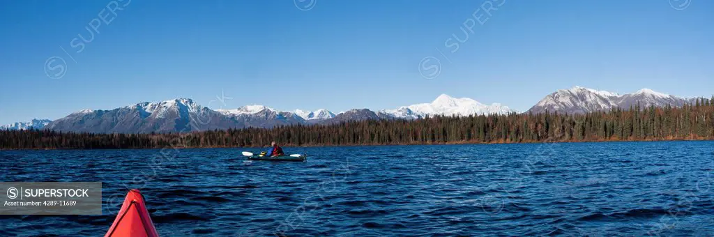Woman kayaking in Byers Lake as seen from another kayaker´s point of view with scenic view of Mt. McKinley on a clear sunny day, Denali State Park, So...