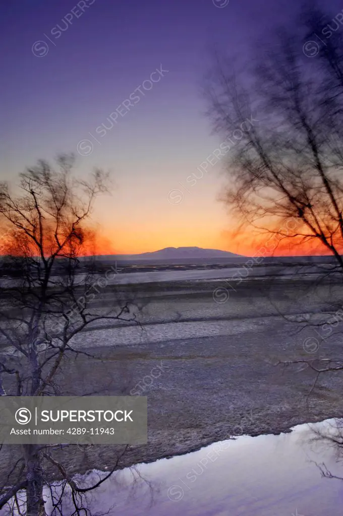 Sun setting behind Mt. Susitna as viewed from the Tony Knowles Coastal Trail in Kincaid Park in Anchorage, Southcentral Alaska, Winter