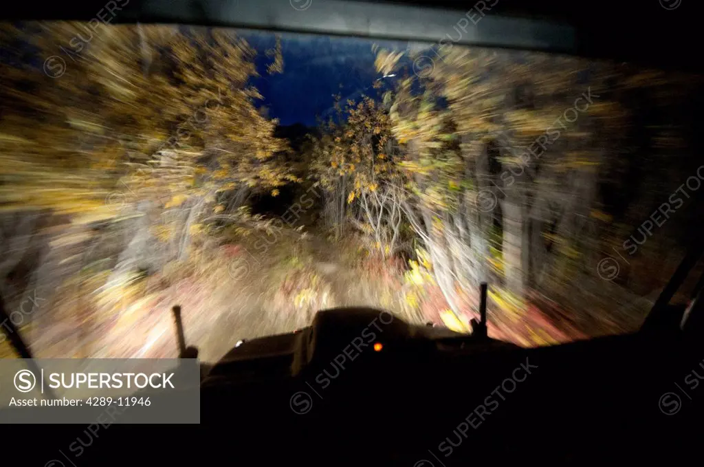 Night view from inside an Argo amphibious all_terrain vehicle driving on a tree_lined trail in the John River valley in Gates of the Arctic National P...
