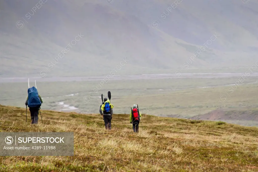 Group with packrafts on tundra in rainy weather to packraft the Sanctuary River, Denali National Park & Preserve, Interior Alaska, Summer