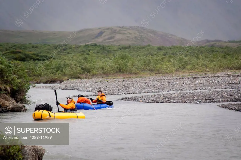 Two women packrafting the Sanctuary River in rainy weather, Denali National Park & Preserve, Alaska Range, Interior Alaska, Summer