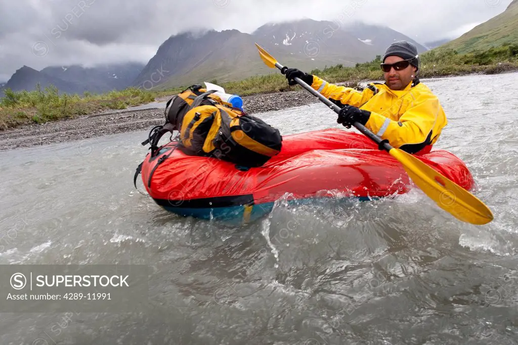 Man packrafting the Sanctuary River in rainy weather, Denali National Park & Preserve, Alaska Range, Interior Alaska, Summer