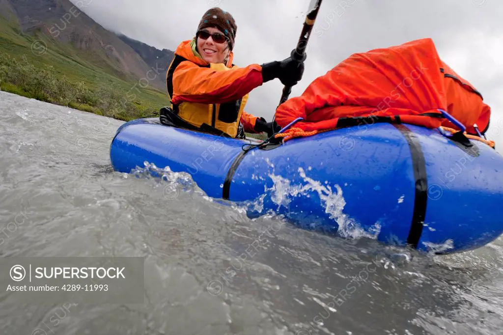 Woman packrafting the Sanctuary River in rainy weather, Denali National Park & Preserve, Alaska Range, Interior Alaska, Summer