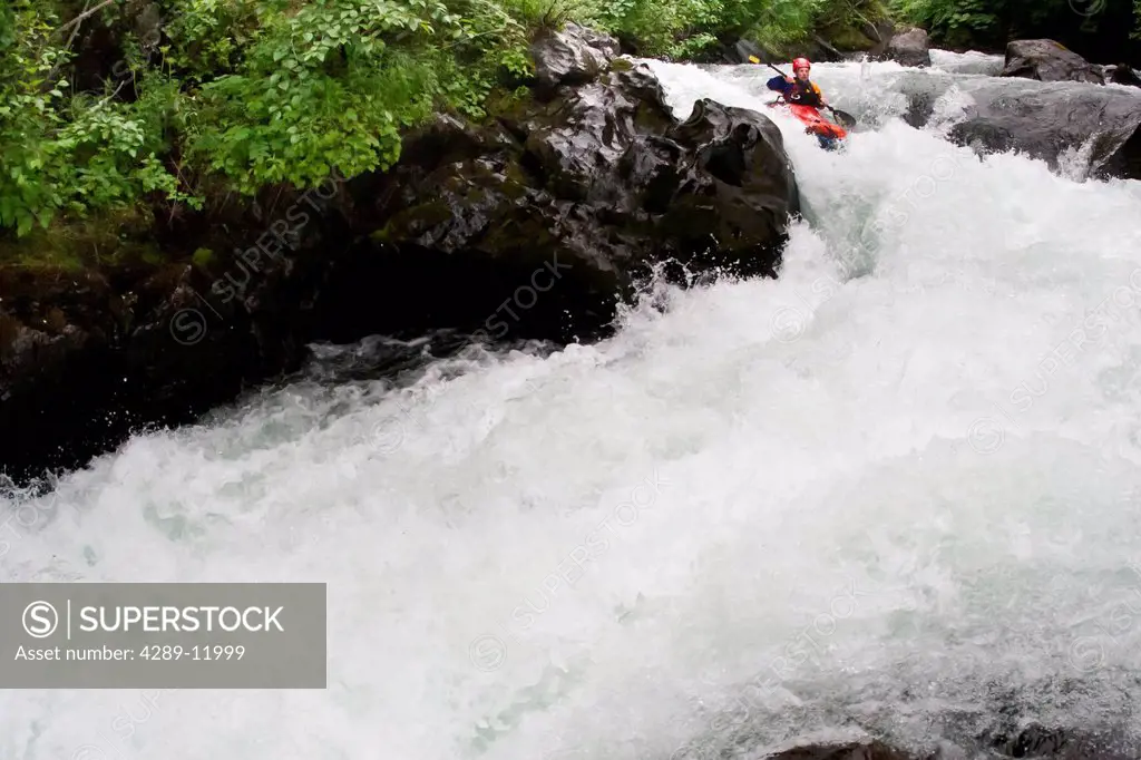 Man packrafting whitewater in a narrow canyon of lower Ship Creek near Anchorage, Southcentral Alaska, Summer