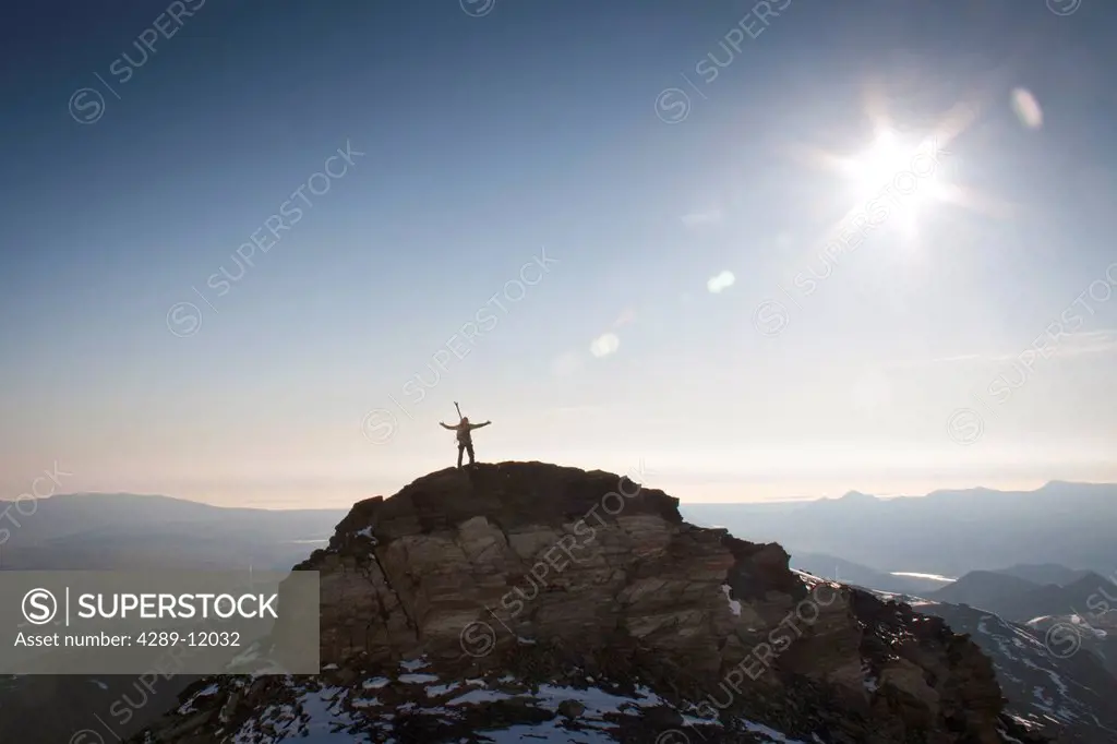 Hiker silhouetted against the Arctic Coastal plane on the north ridge of Mount Chamberlin, Brooks Range, Arctic National Wildlife Refuge, Summer in Ar...