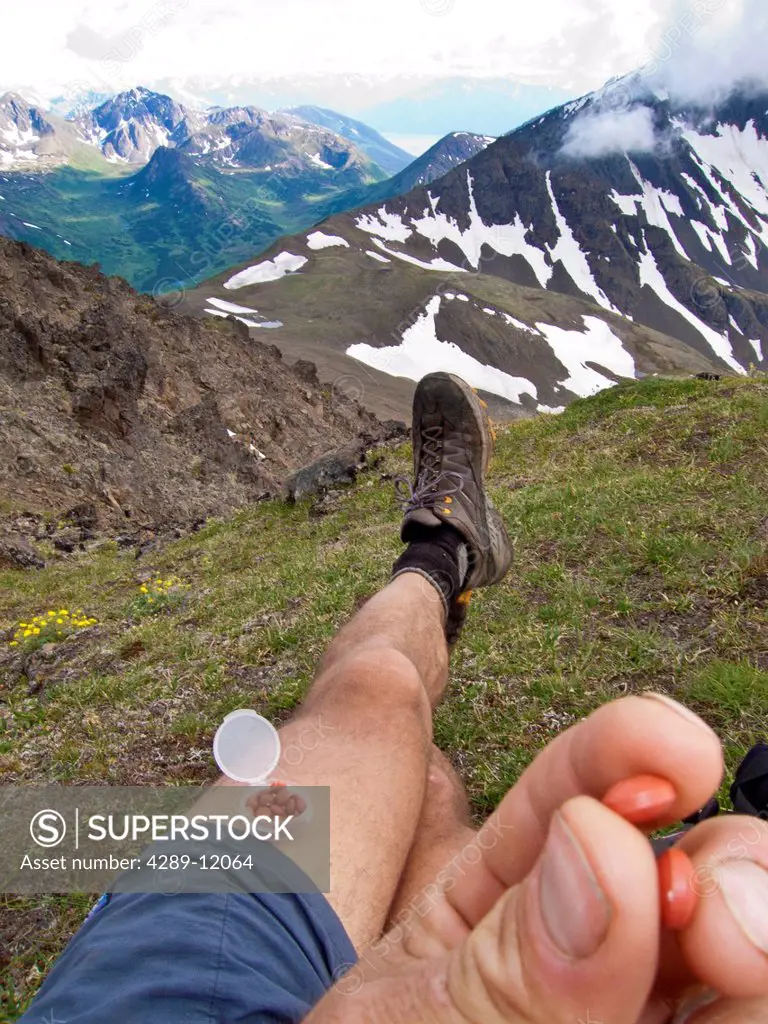 Trail runner rests and takes ibuprofen in the front Chugach Mountains, near Anchorage, Chugach State Park, Summer in Southcentral Alaska