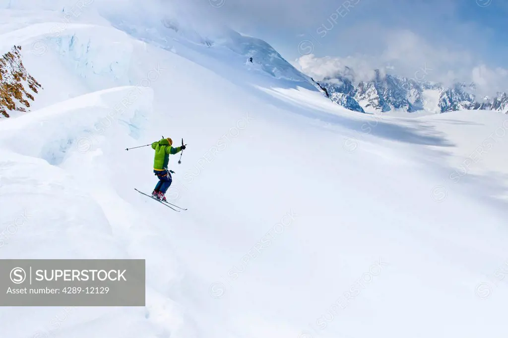 Skier jumping a bergschrund crevasse onto powder on Hayes Glacier, Tordrillo Mountains, Winter in Southcentral Alaska