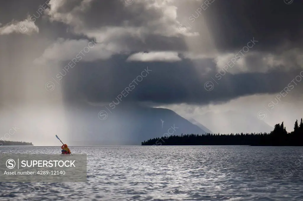Woman sea kayaking during rain storm on Lake Nerka, Wood Tikchik State Park, near Dillingham, Summer in Southwest Alaska