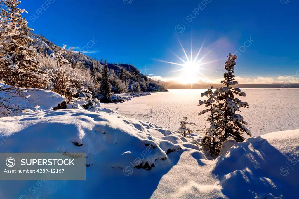 Winter sun shines just over the horizon along the shoreline of Skilak Lake, Kenai National Wildlife Refuge, Southcentral Alaska, Winter, HDR