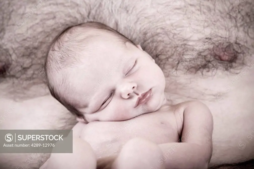 Close up of sleeping newborn infant being held against a man´s bare chest Alaska United States