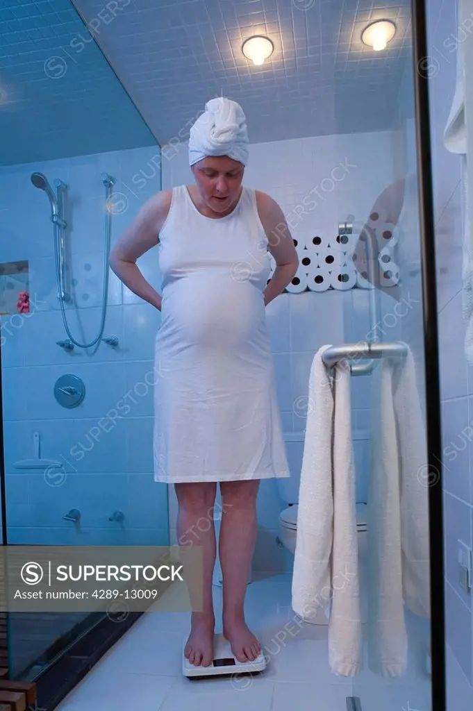 Pregnant woman weighing herself on bathroom scales Alaska United States