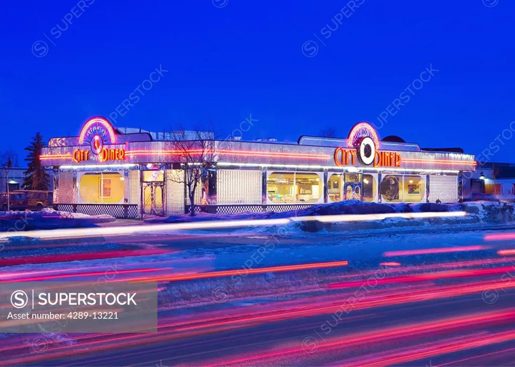 Blurred vehicle tailights pass in front of a Retro 60´s looking diner with silver trim and neon lights in Anchorage, Alaska.