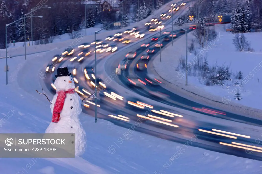 View of traffic near downtown Anchorage with a snowman in the foreground, Southcentral Alaska, Winter. Digital enhanced