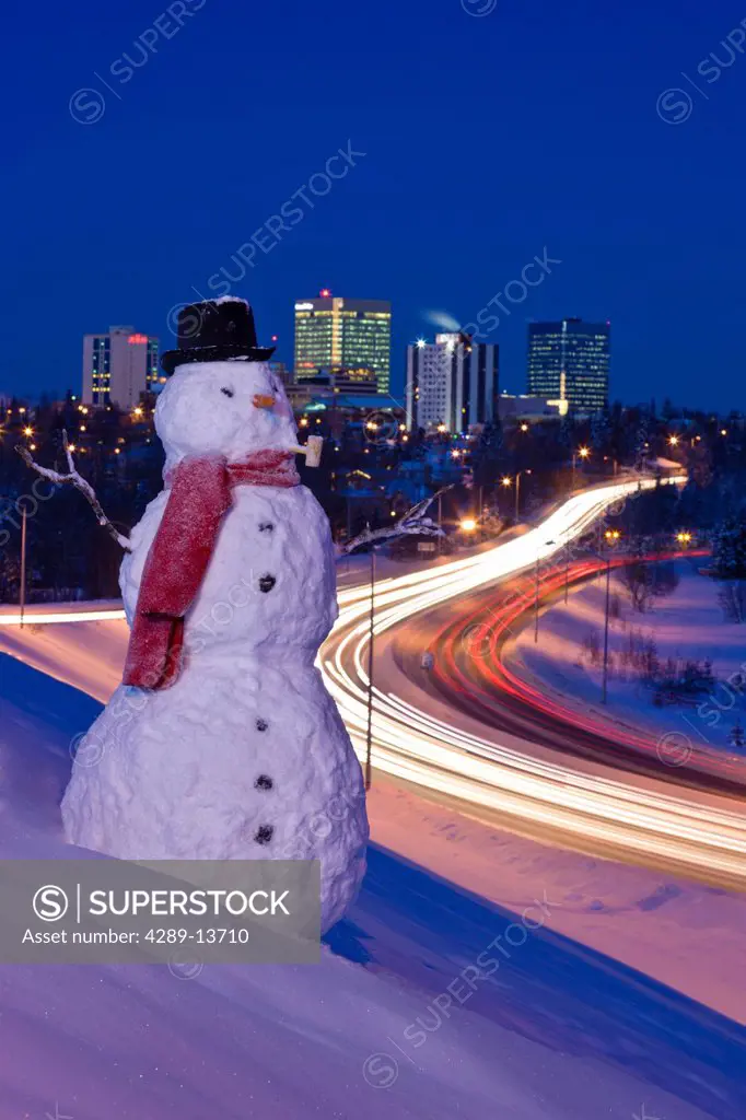 View of traffic and downtown Anchorage with a snowman in the foreground, Southcentral Alaska, Winter. Digitally enhanced.