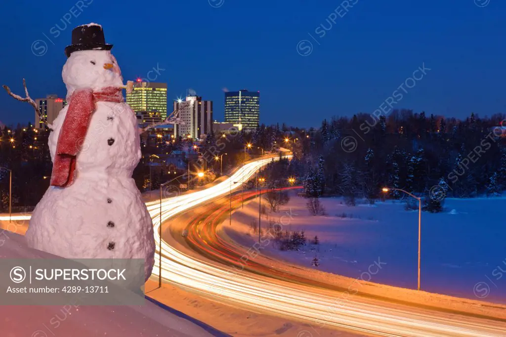 View of traffic and downtown Anchorage with a snowman in the foreground, Southcentral Alaska, Winter. Digitally enhanced.