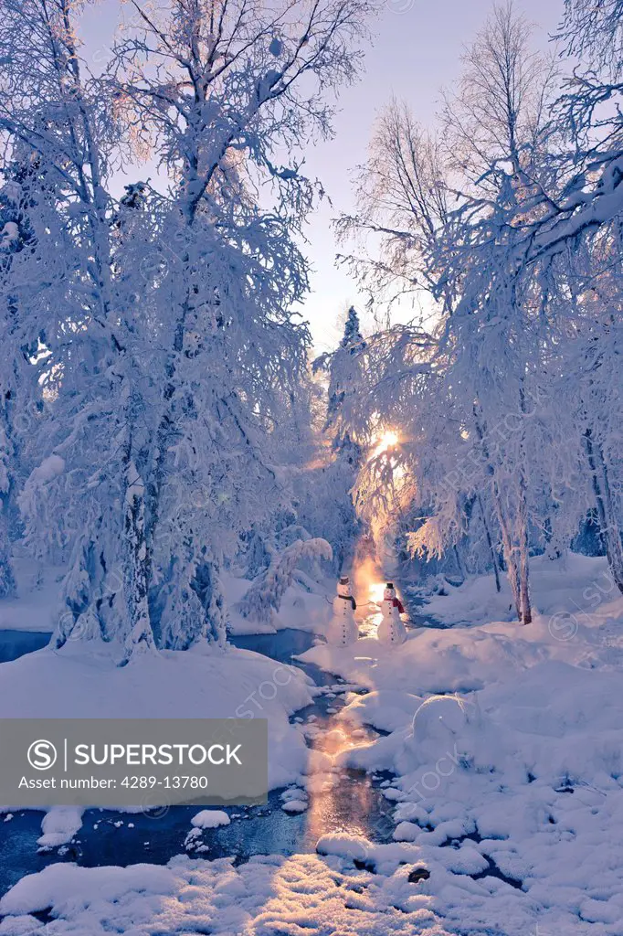 Snowman couple standing next to a stream with sunrays shining through fog and hoar frosted trees in the background, Russian Jack Springs Park, Anchora...