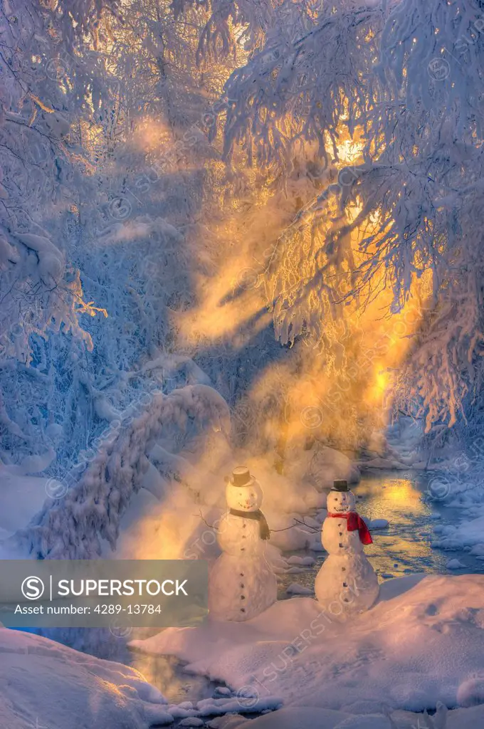 Snowman couple standing next to a stream with sunrays shining through fog and hoar frosted trees in the background, Russian Jack Springs Park, Anchora...