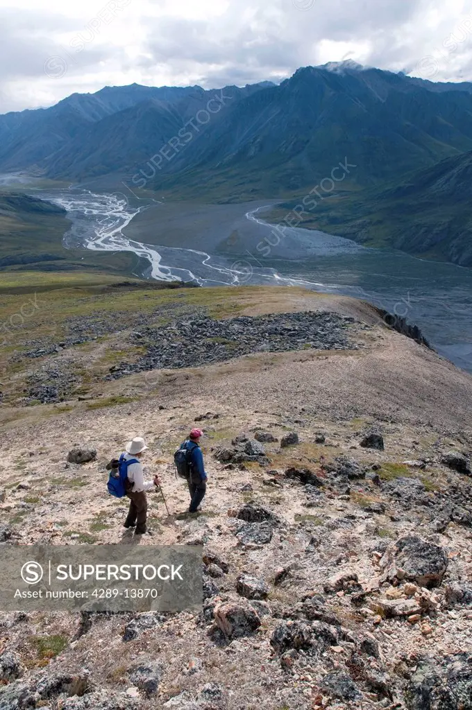Mature hikers descend a ridge above the Marsh Fork of the Canning River in the Brooks Range, Arctic National Wildlife Refuge, Alaska, Summer
