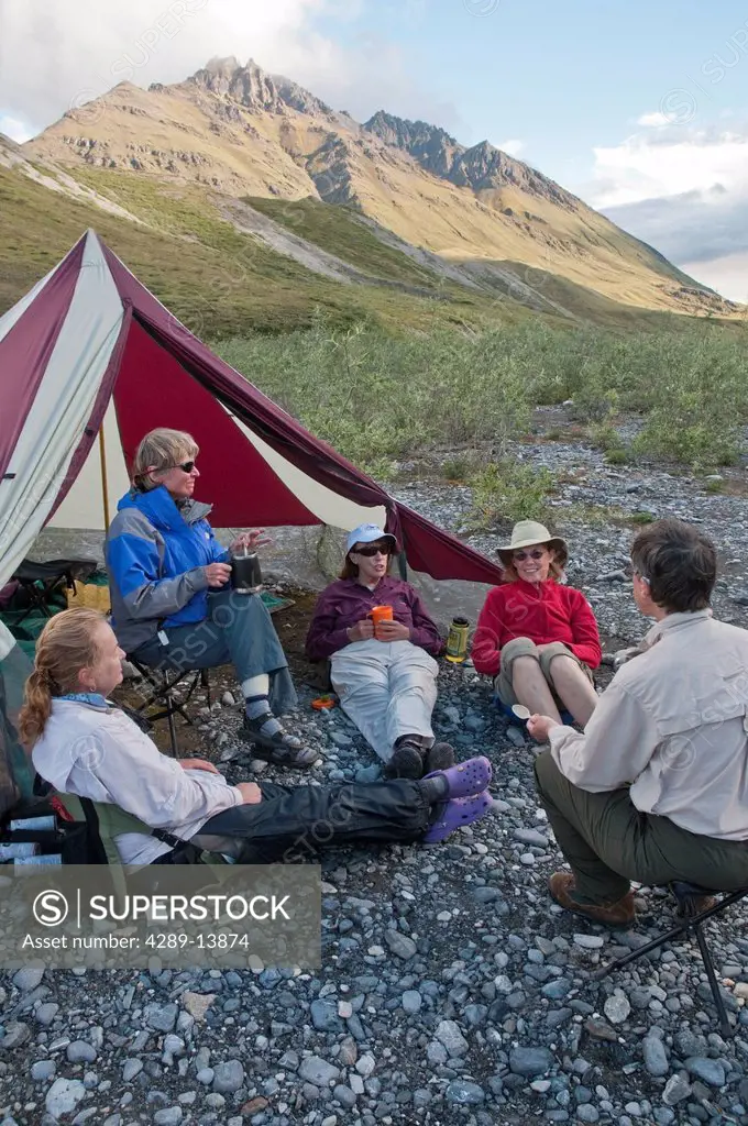 Mature female hikers relax at campsite along the Marsh Fork of the Canning River in the Brooks Range, Arctic National Wildlife Refuge, Alaska, Summer