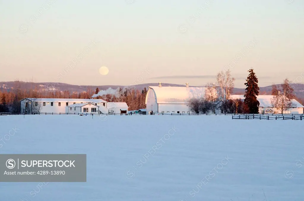 Full moon rises over snowcovered historic buildings of former dairy farm at Creamer´s Field Migratory Waterfowl Refuge, Fairbanks, Interior Alaska, Wi...