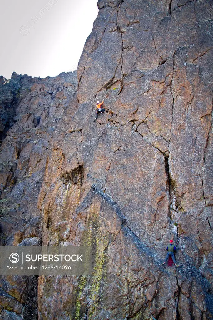 Two men rock climbing a vertical rock wall on The Wedge, Chugach Mountains, Southcentral Alaska, Autumn