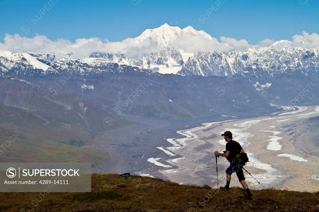 Silhouette of a man hiking in the Tokosha Mountains above the Tokositna Glacier with Mt. Hunter and the Alaska Range in the background, Denali Nationa...