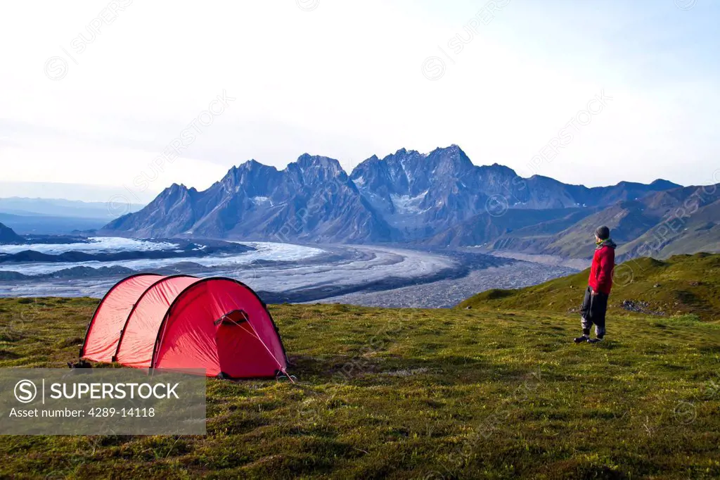 Male backpacker at camp above the Ruth Glacier with the Tokosha Mountains beyond, Denali National Park & Preserve, Interior Alaska, Autumn