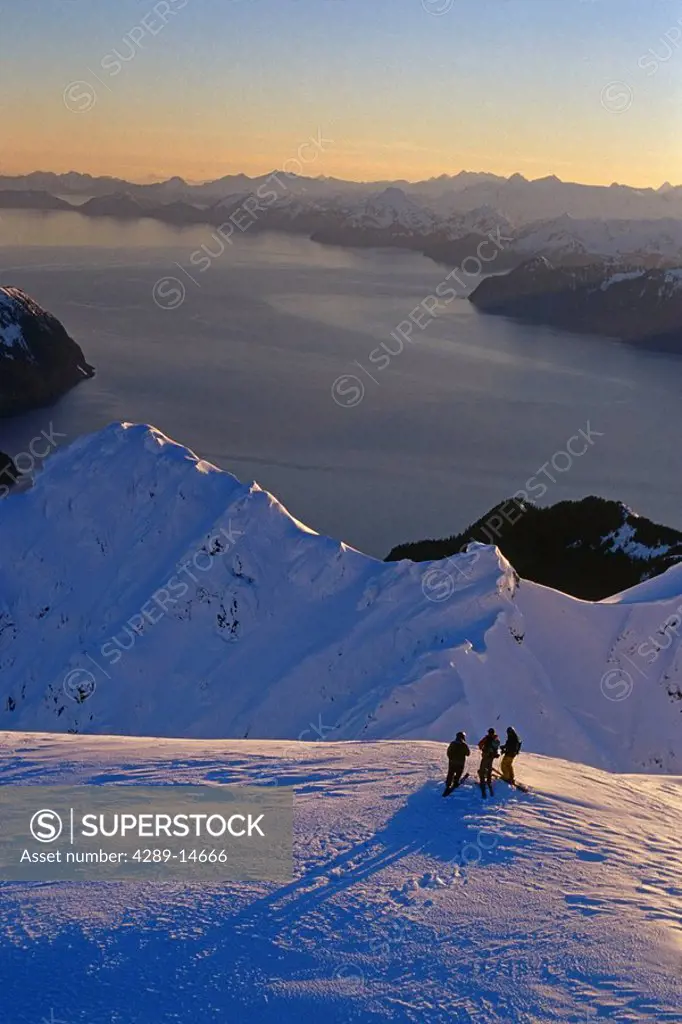 Aerial of 3 extreme skiers atop ridge Kenai Mtns @ sunrise w/Resurrection Bay in distance Alaska Winter