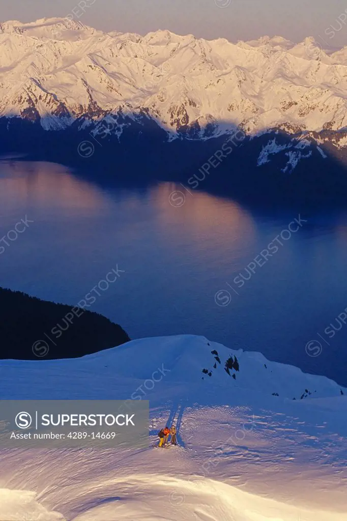 Aerial of 3 extreme skiers atop ridge Kenai Mtns @ sunrise w/Resurrection Bay in distance Alaska Winter