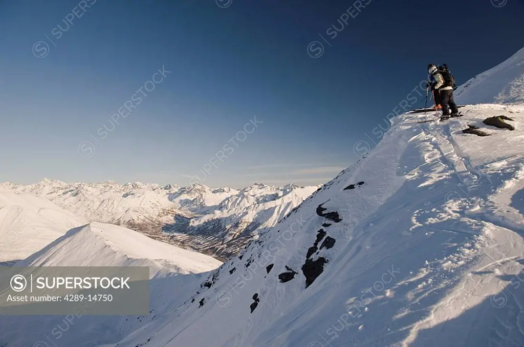 Two backcountry skiers peer over the edge to scout out their decent in Hatcher Pass, Southcentral Alaska